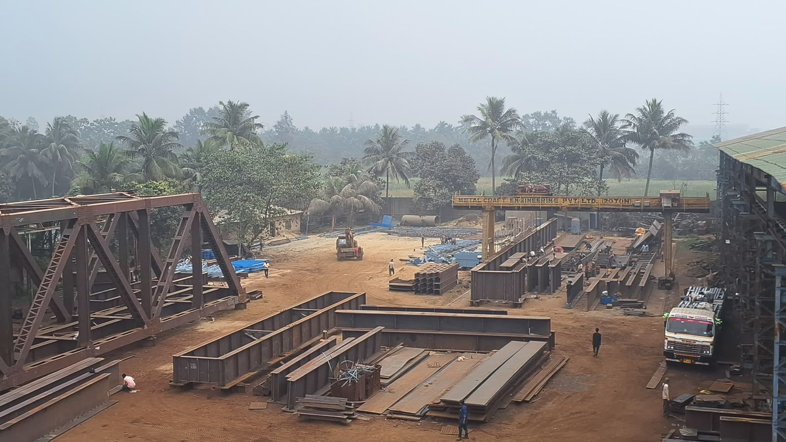 Steel trusses and structural sections arranged across the fabrication yard