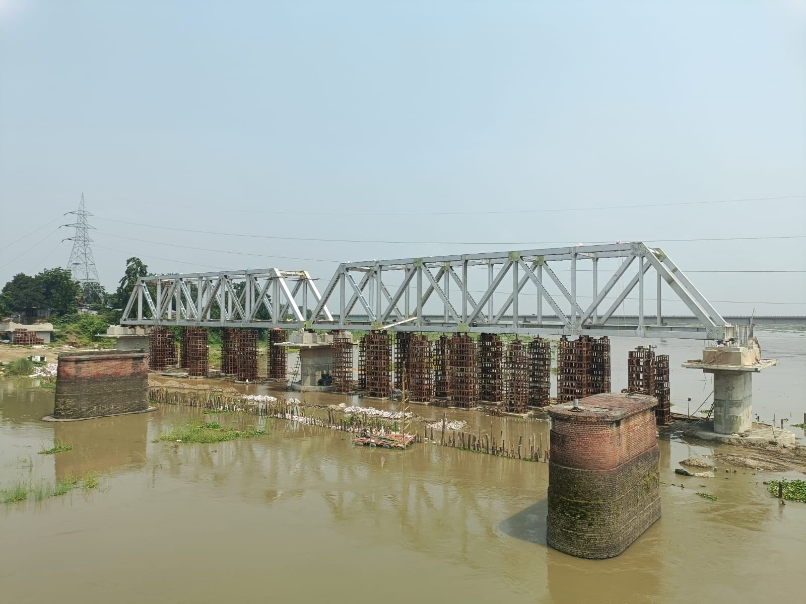 Completed steel truss bridge spanning a river on concrete piers