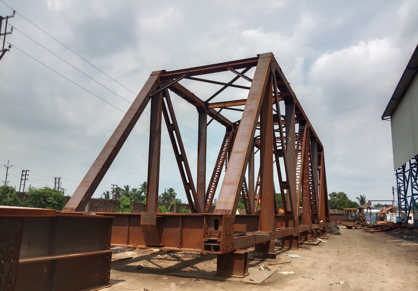Primed steel truss girder standing in the yard