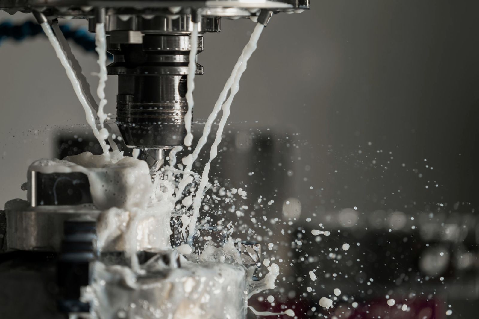 CNC milling cutter working a steel part under coolant spray